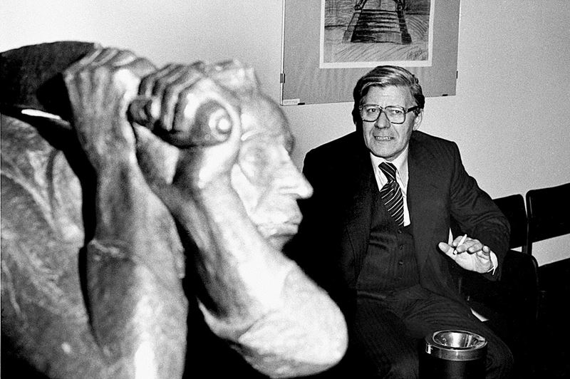 Helmut Schmidt sitzend und rauchend, im Vordergrund ist eine Skulptur des Künstlers Ernst Barlach zu sehen.