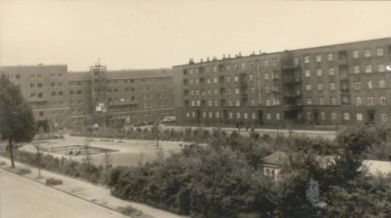 A five-storey block of flats on Schwalbenplatz: playgrounds and a green space are located between the buildings.